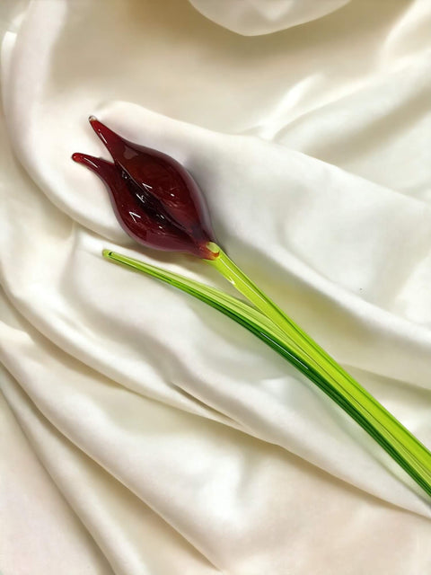 a red flower sitting on top of a white sheet