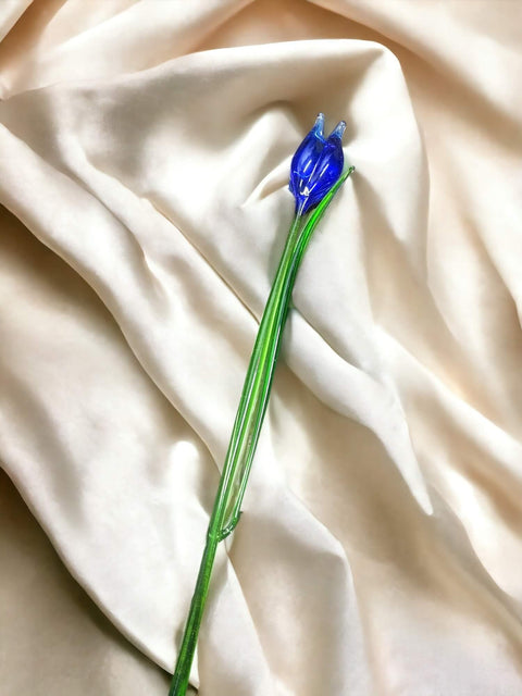 a blue flower sitting on top of a white cloth