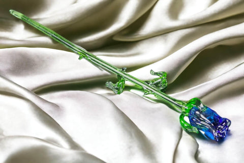 a single blue flower sitting on top of a white cloth