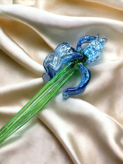 a blue glass flower sitting on top of a white cloth