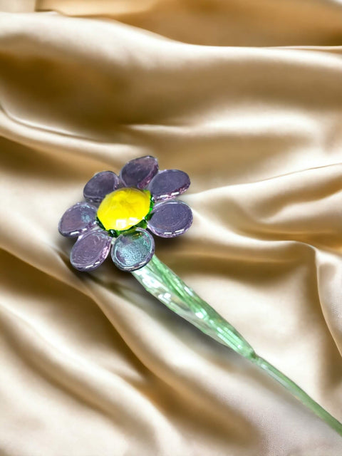 a purple and yellow flower sitting on top of a white satin