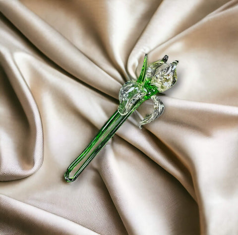 a green glass flower on a satin fabric