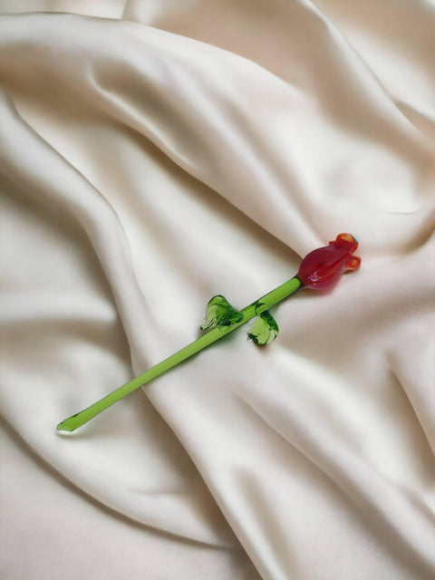 a single red flower on a white cloth