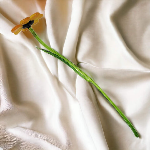 a single yellow flower sitting on top of a white sheet