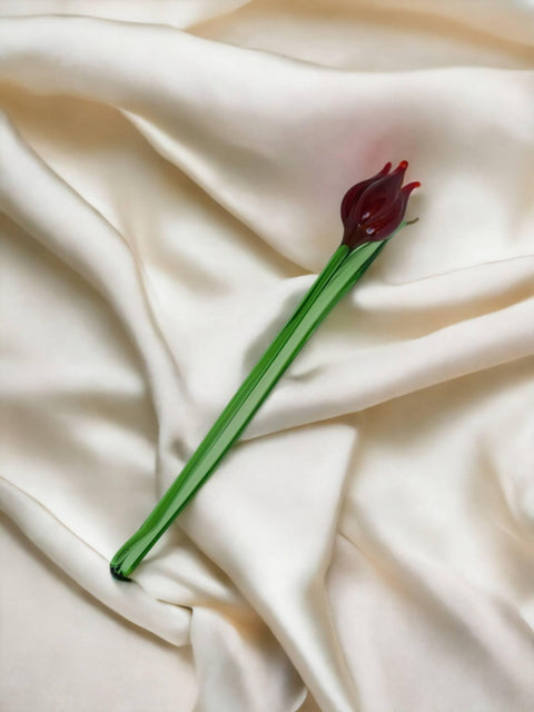 a single red flower on a white cloth