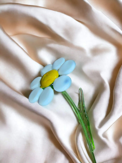 a blue and yellow flower laying on a white cloth