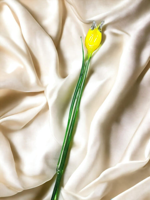 a single yellow flower on a white cloth