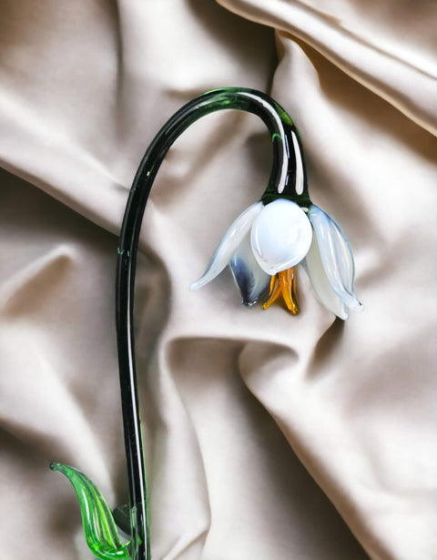 a white flower with a green stem on a white cloth