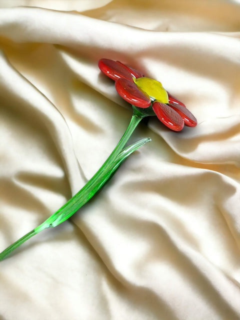 a red flower sitting on top of a white sheet