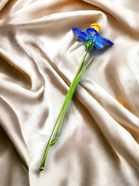 a blue flower laying on top of a white sheet