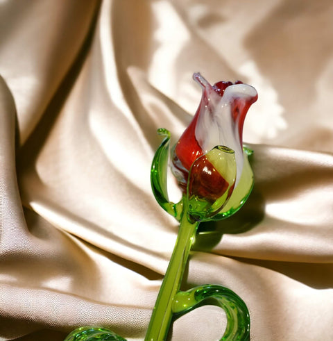 a glass flower is sitting on a white cloth