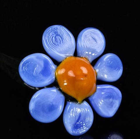 a blue and orange flower brooch sitting on top of a table