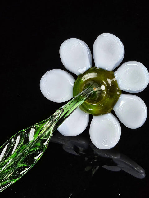 a glass flower with a green stem on a black surface