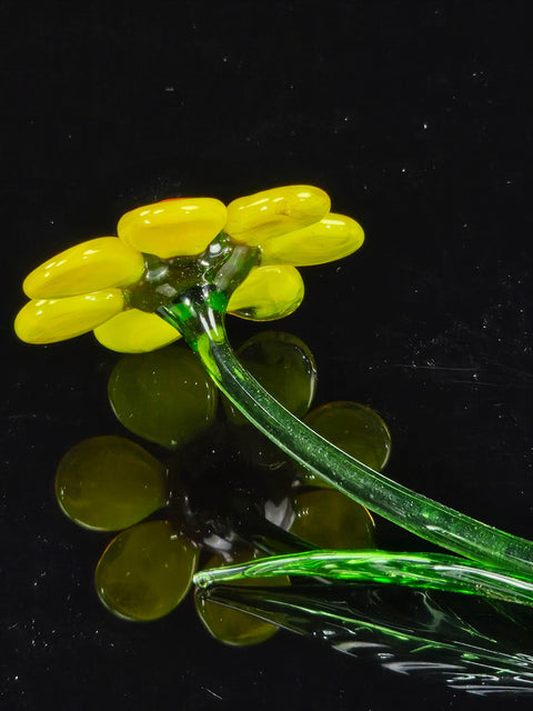 a yellow flower sitting on top of a black surface