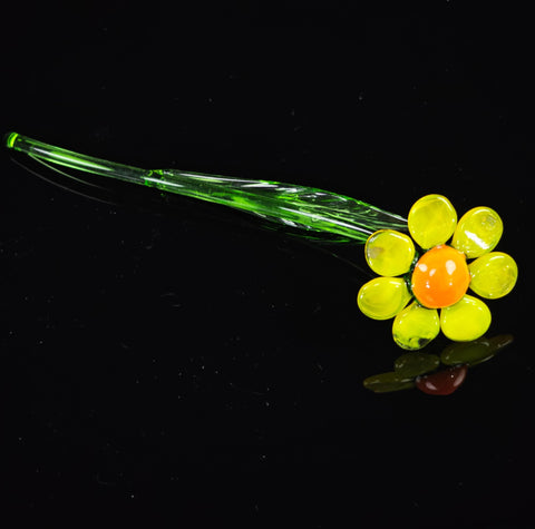 a yellow and green flower sitting on top of a black surface