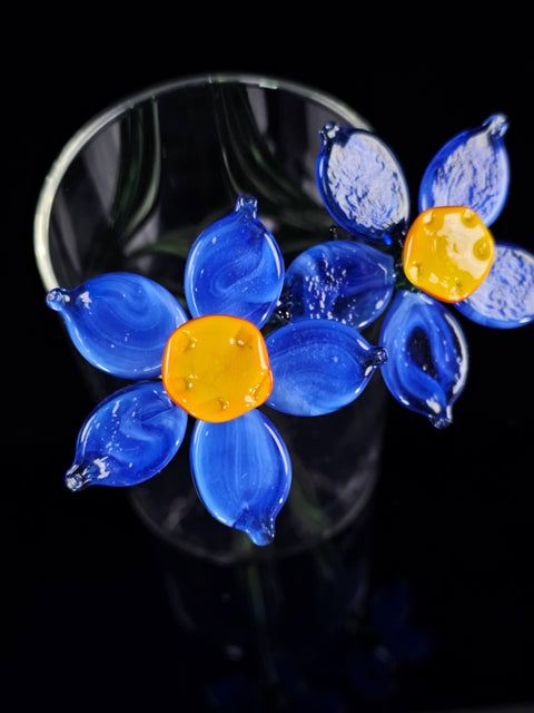 a glass vase filled with blue and yellow flowers