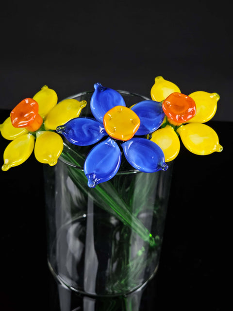 a glass vase filled with yellow and blue flowers