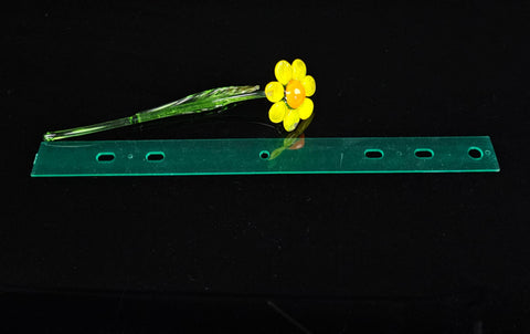 a yellow flower sitting on top of a green piece of plastic