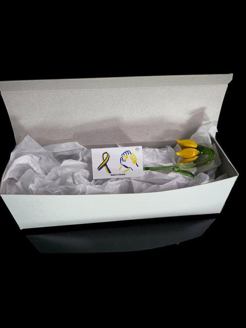 a yellow flower in a white box with tissue paper