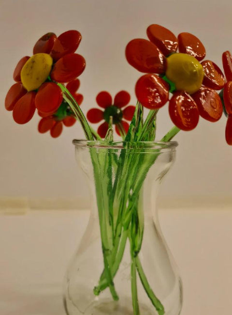 a glass vase filled with red and yellow flowers